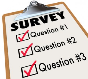 A checklist on a wooden clipboard with the word Survey and a list of questions to gather customer or audience feedback, reviews and reactions to important matters or products